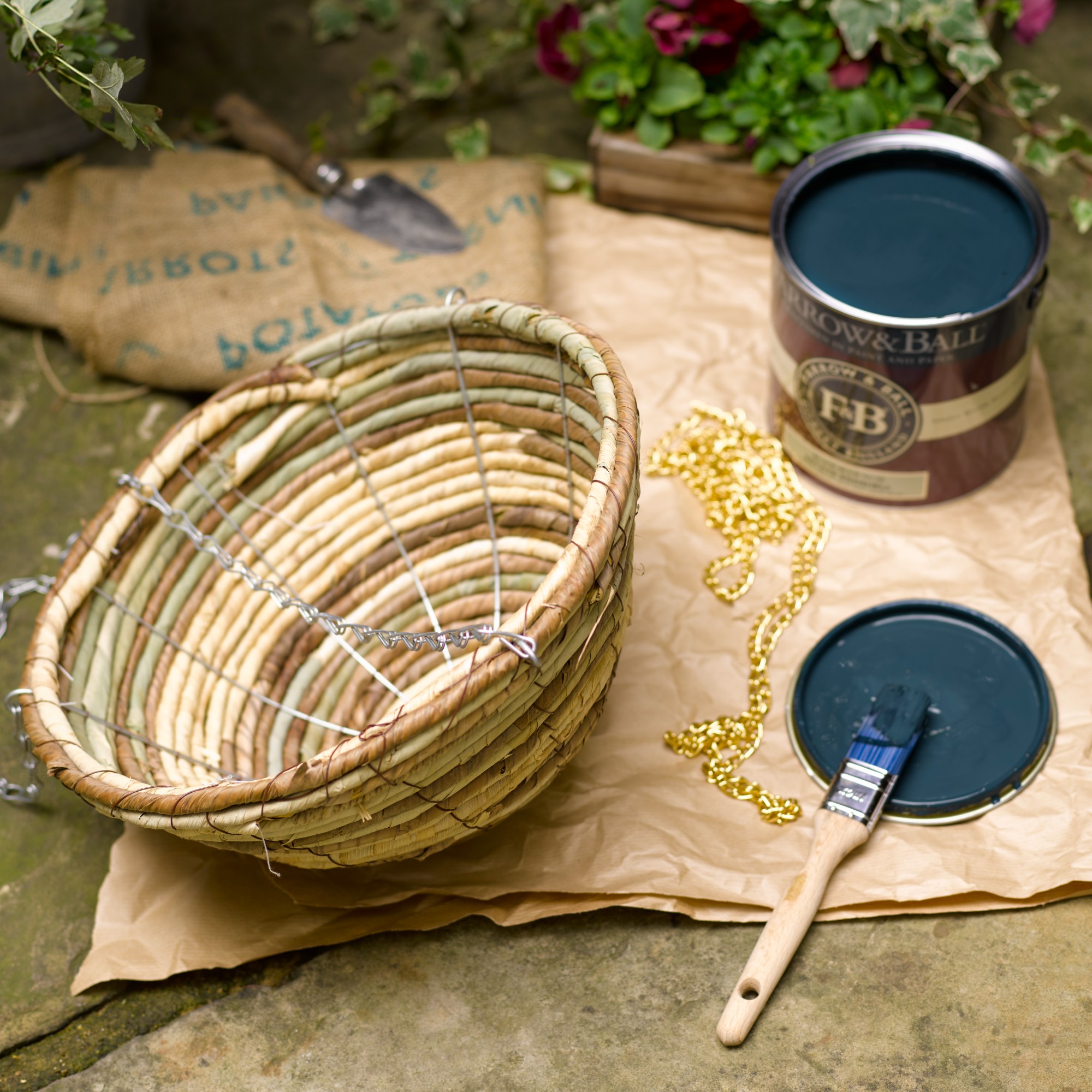 An open tin of Farrow &amp;amp; Ball blue tin of paint next to a hanging garden plant basket