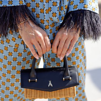 woman with strawberry jell-o nails holding handbag wearing blue patterned suit