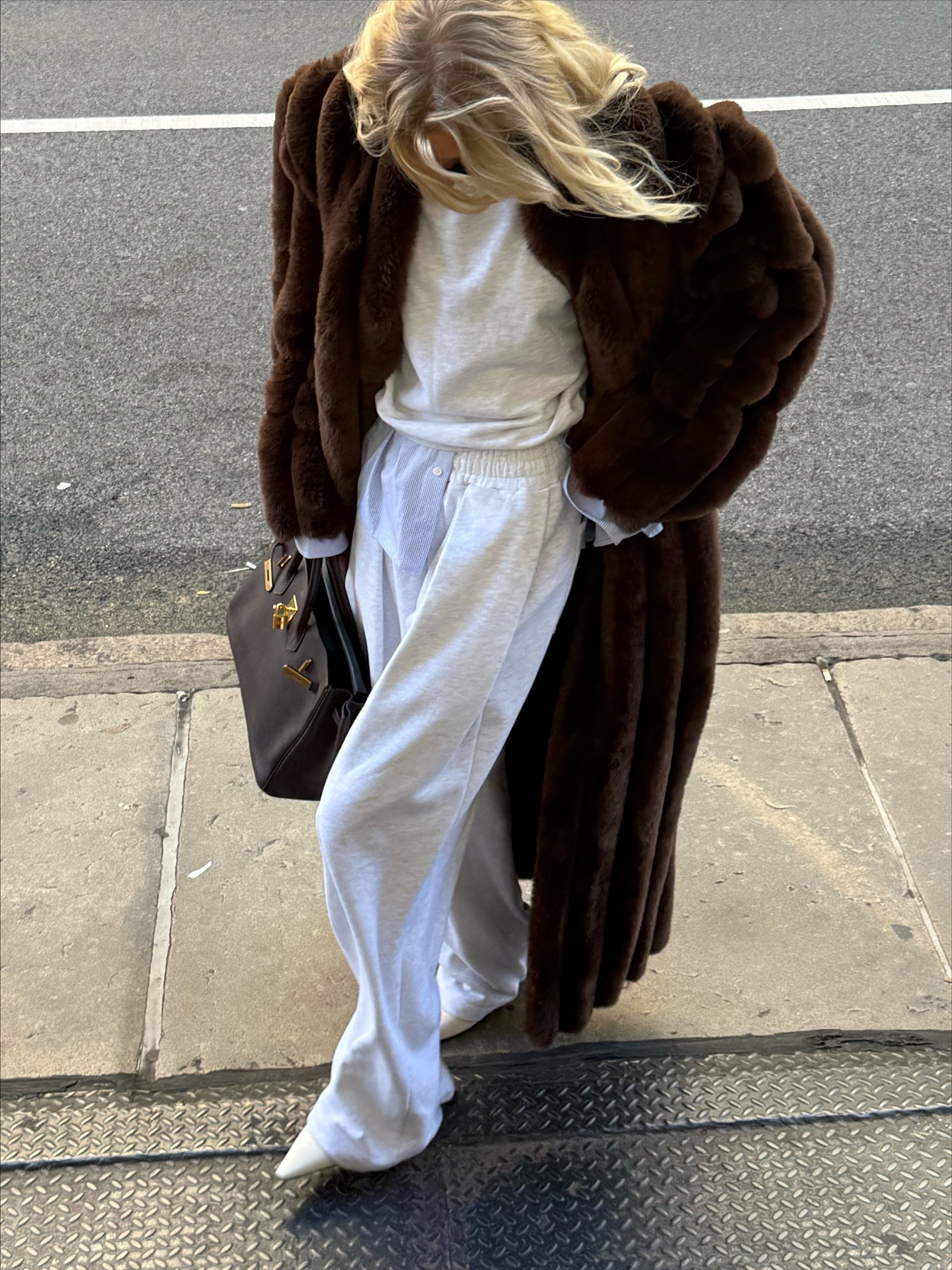 Elsa Hosk wearing gray sweatpants, a matching sweatshirt, and a long brown fur coat with a Birkin bag.