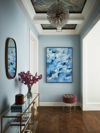 a blue entryway with a stool and flowers