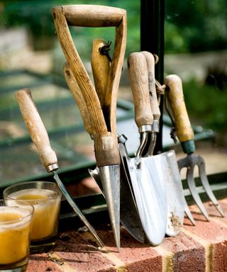 A set of garden hand tools leaning against a wall