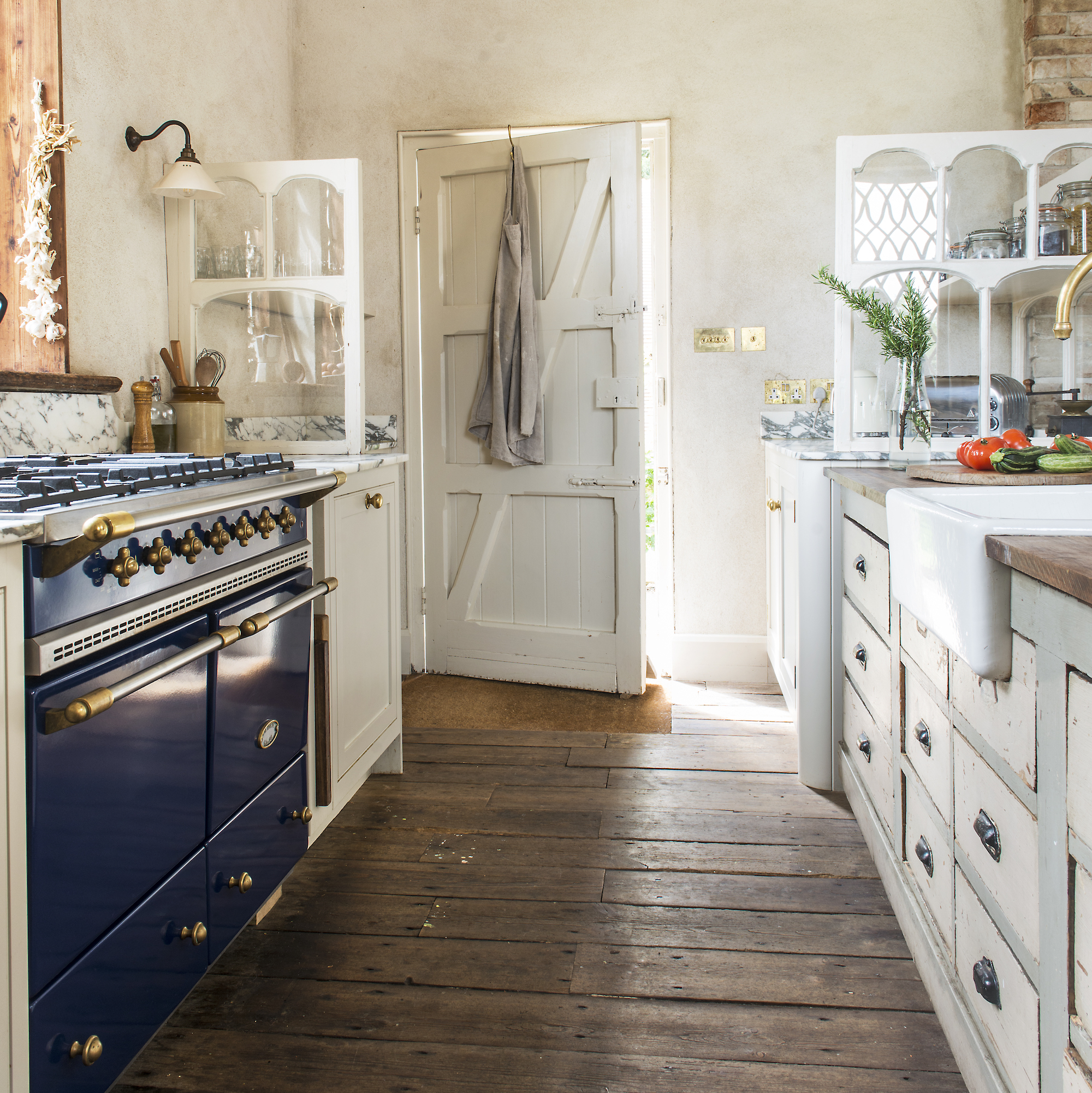 galley kitchen with large blue range cooker, wooden floor and white vintage drawer units