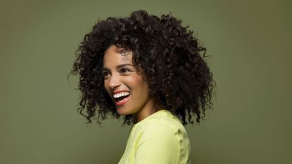 best shampoo for curly hair - woman with beautiful curls and big smile on a green background - getty images 528770255