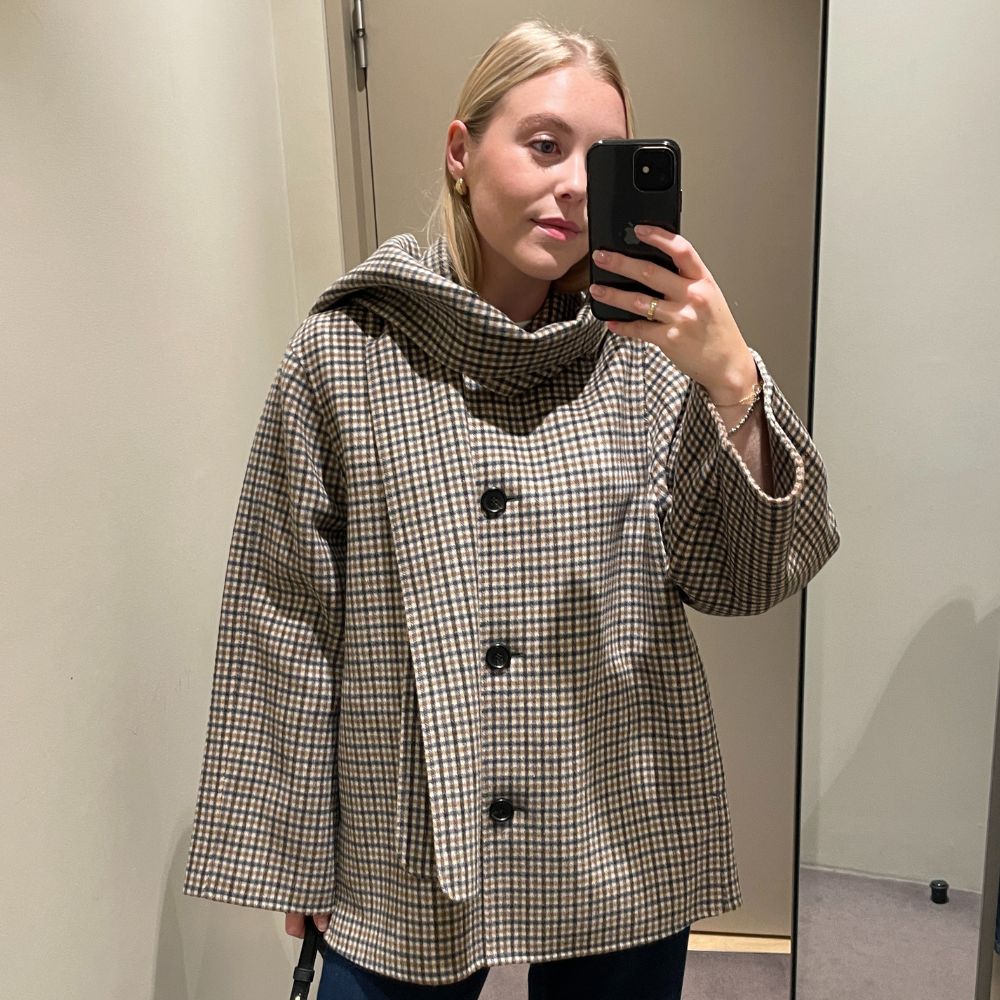Woman wears check scarf jacket and blue jeans