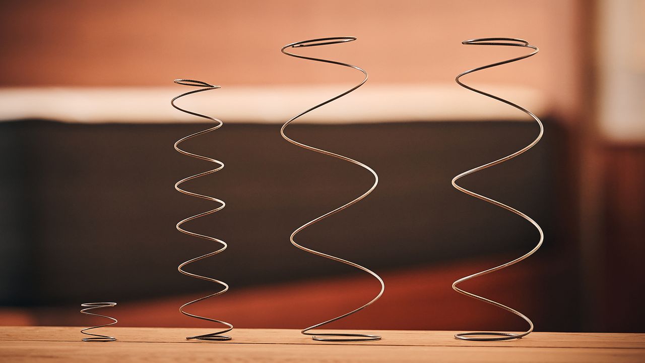 This image shows a series of types of mattress coils, arranged in a line. On the left is a microspring mattress coil, next to a small zoned coil. On the right are two standard mattress coils.