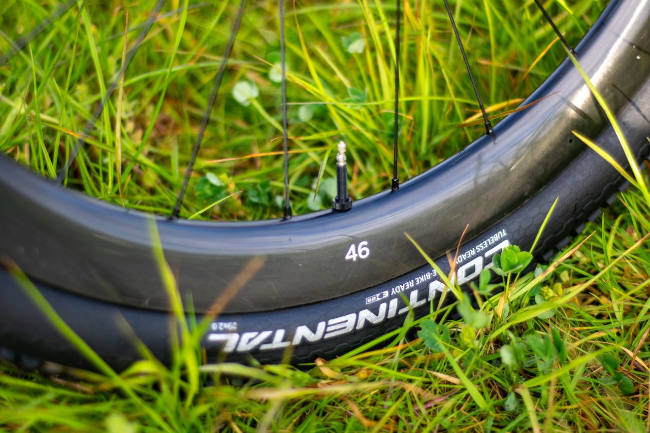 A blue Factor Sarana gravel bike in a grassy field with a hedge in the background