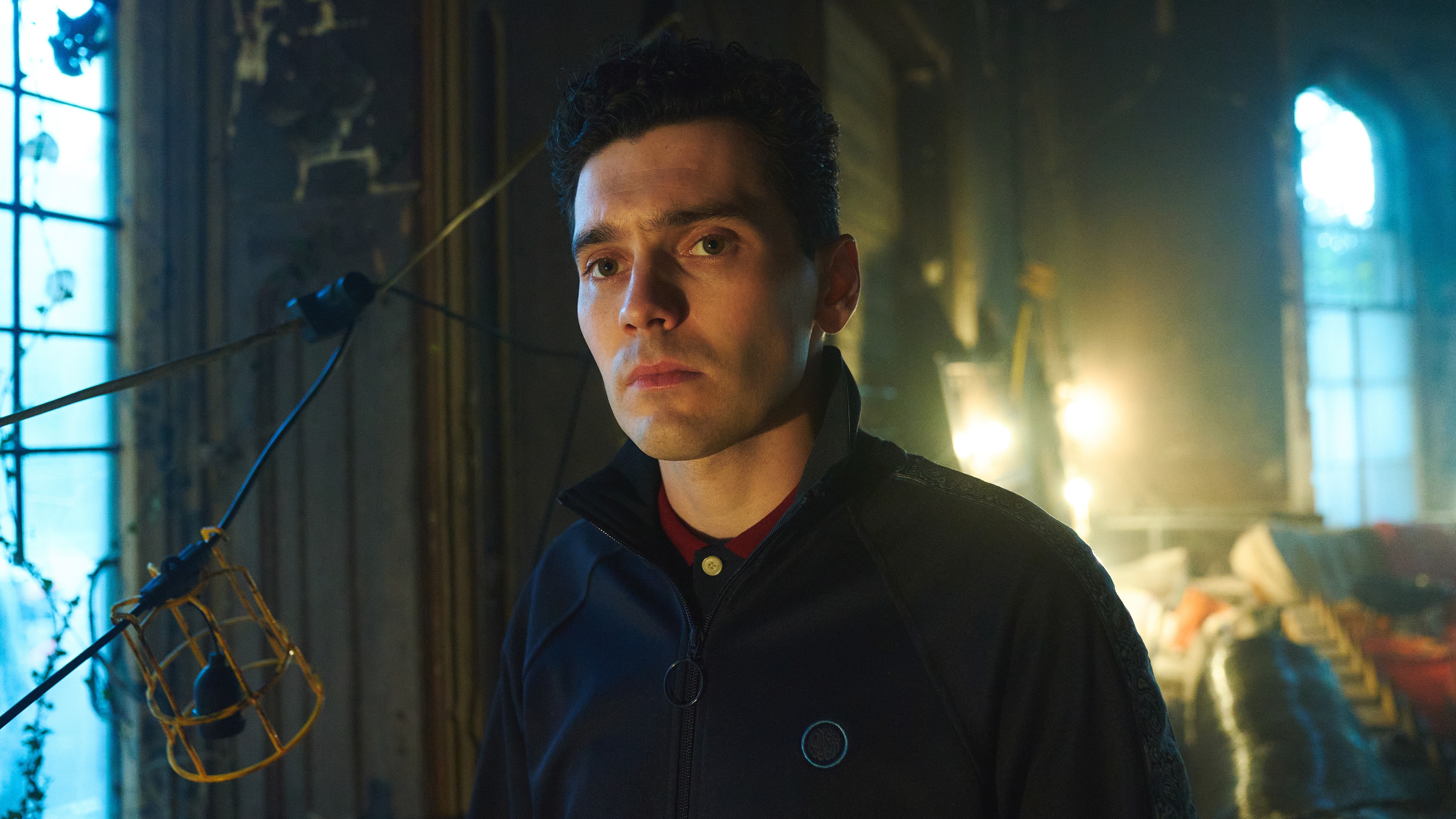 Charlie Green (JACK ROWAN) standing in an old house looking serious