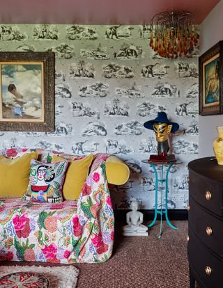 living room with dinosaur wallpaper and yellow sofa with floral throw