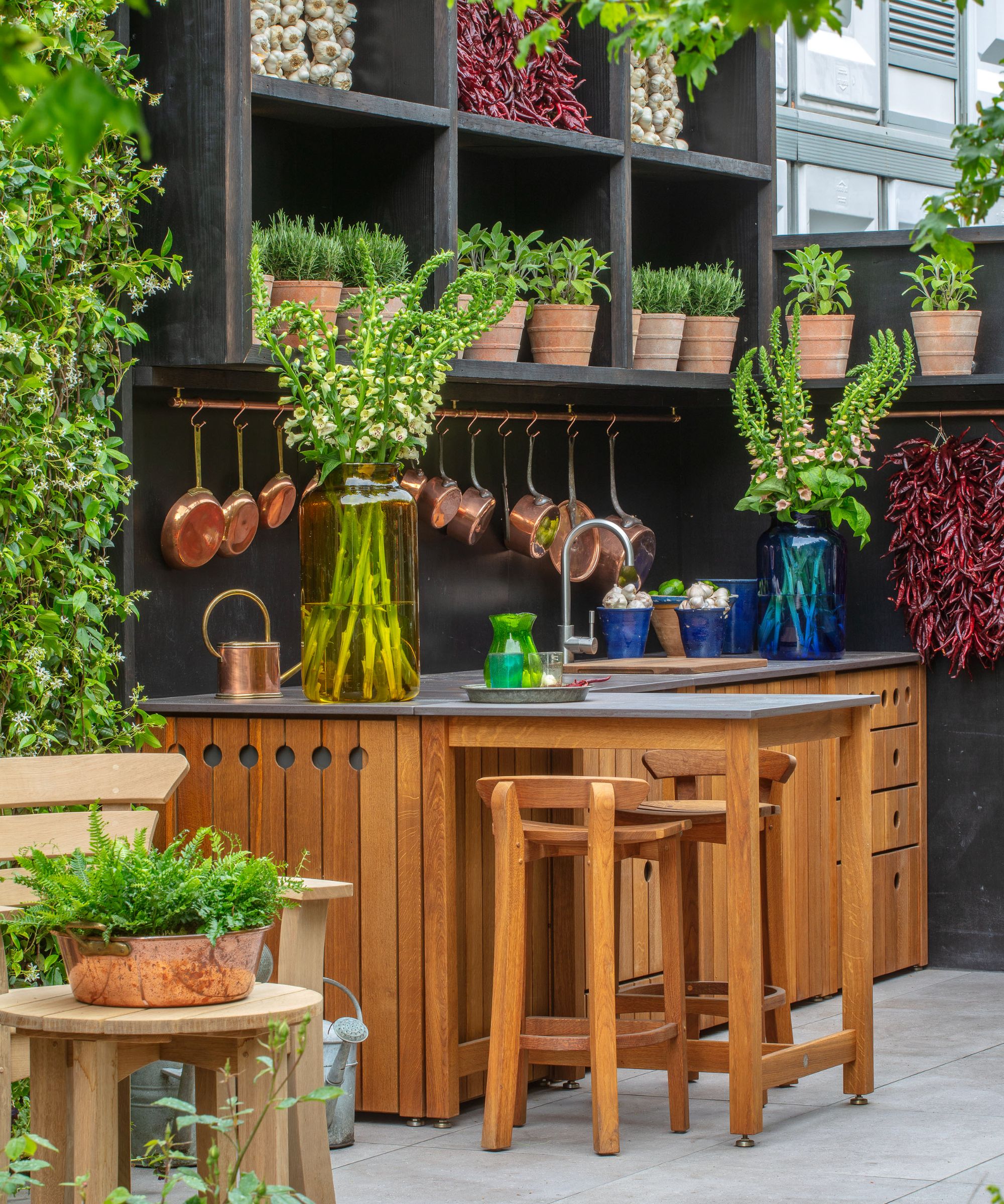 Wooden outdoor bar with shelves behind with terracotta pots of herbs