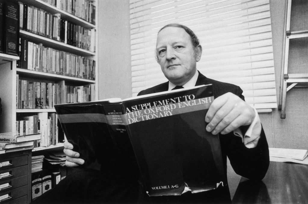 English writer and broadcaster Robert Robinson holding the first volume of 'A Supplement To The Oxford English Dictionary