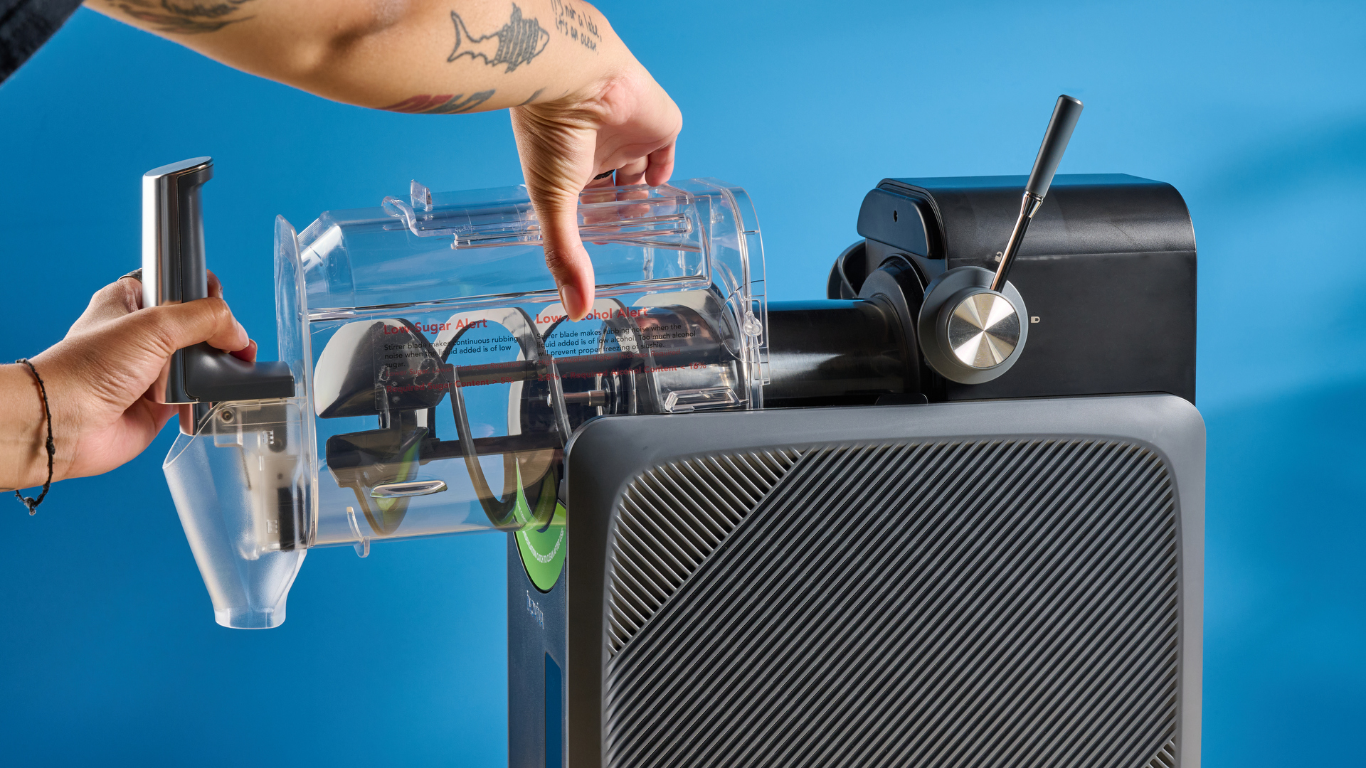 the inoviva slushie machine, a slushie maker with a plastic cylinder body, a dispensing spout, photographed making orange juice slush against a blue tom&#039;s guide background