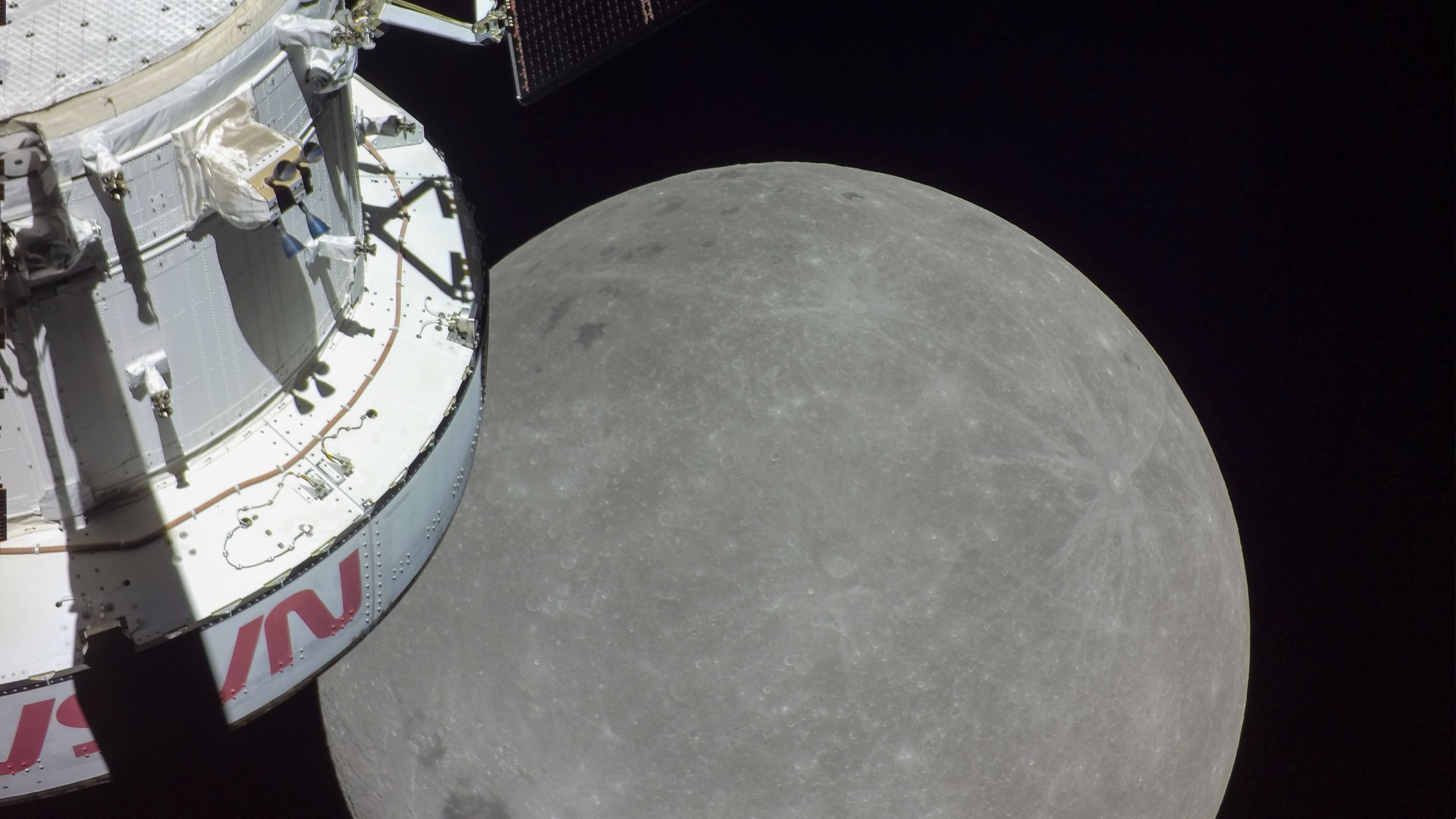 the moon, as seen from lunar orbit by nasa's artemis 1 orion spacecraft. part of the capsule is visible in the foreground.