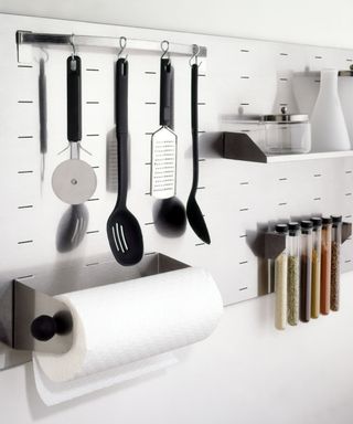 A kitchen peg board with hooks and utensils