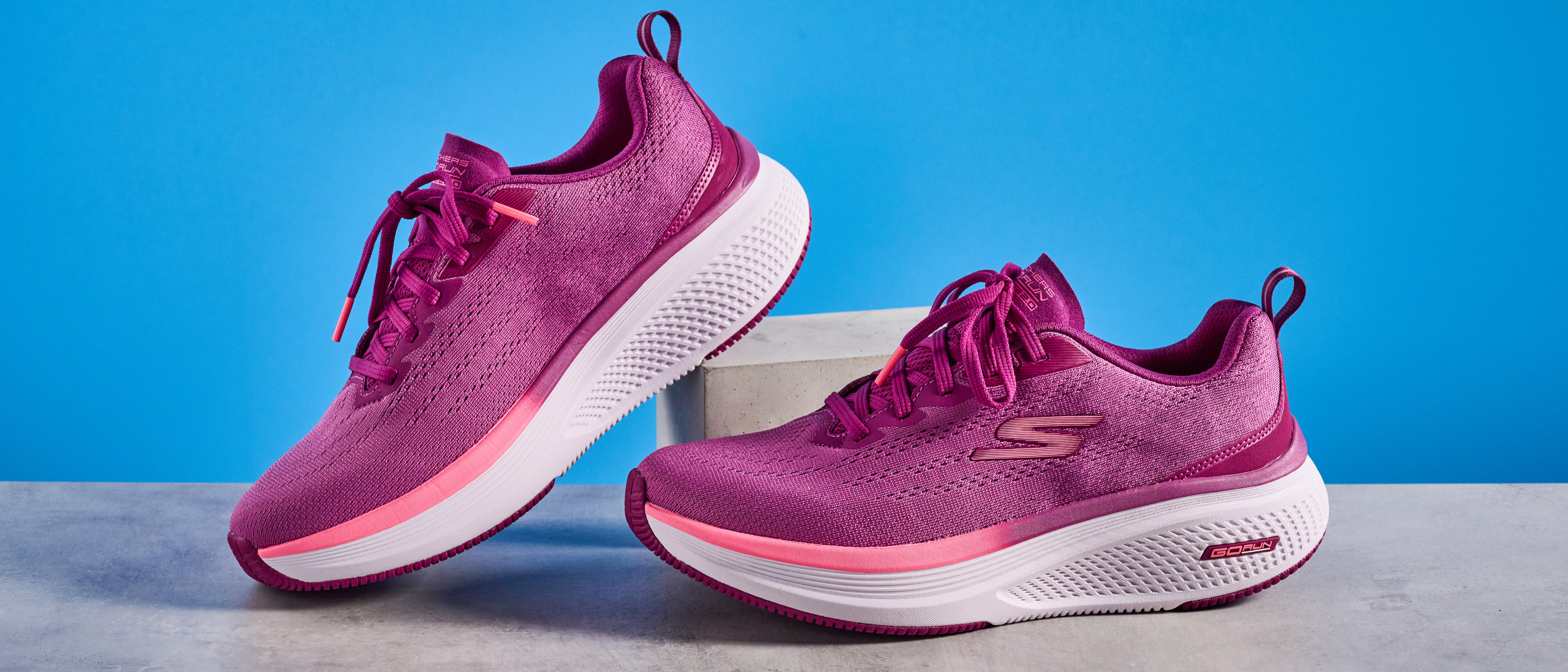 the skechers go run elevate 2.0 running shoes in the women&#039;s style, in fuchsia pink, photographed against a blue background