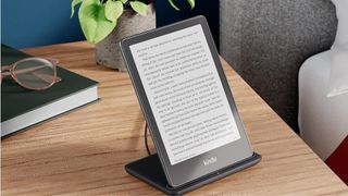 The Kindle Paperwhite charging on a bedstand