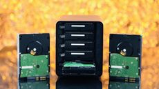 A NAS drive and hard disks against a yellow background