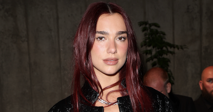 dua lipa wears a black jacket that contrasts her red hair