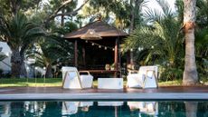 An outdoor garden with a pool and white deck furniture