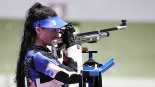 Mary Tucker takes aim at the 10m Air Rifle Women&#039;s event at the Olympic Games, wearing a blue and white jacket and blue visor.