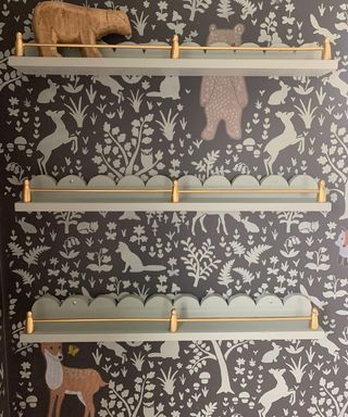 A children's nursery with printed wallpaper and green scalloped wallpaper and gold detail