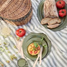 plates and bowls with food on them next to a picnic hamper on a blanket outside, Stacey Solomon's collection with George Home