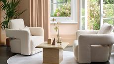 Two cream accent chairs in front of open French doors to a garden