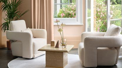 Two cream accent chairs in front of open French doors to a garden