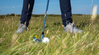 A golfer addressing a golf ball that's in the rough on the 13th hole of Royal Troon