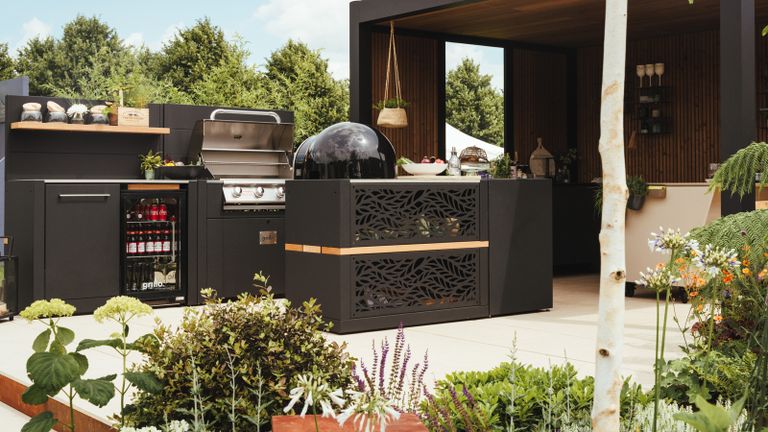 A chic black outdoor kitchen setup with gas grill and outdoor fridge