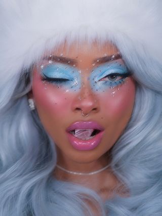 Content creator Nyane Lebajoa wearing an ice queen makeup look featuring bright blue eyeshadow paired with pink cheeks and lips.