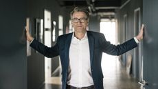 An older businessman stands with his hands pressed against the walls.