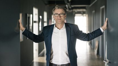 An older businessman stands with his hands pressed against the walls.