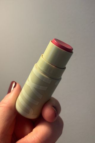 a hand holding pixi balm stick