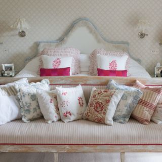 Cream bedroom with patterned wallpaper and pink cushions