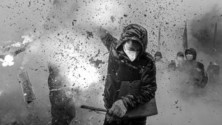 A young man wearing a mask and hood, holding firecrackers in full explosion, encapsulating the cultural tradition of "frying lions" to ward off evil spirits and pray for peace and prosperity.