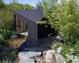A Garden Sanctuary by Hamptons designed by Tony Woods with black decking and garden building at chelsea 2022