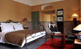 Bedroom of the L’Iglesia Hotel — El Jadida, Morocco with etal bedstewad, wooden furniture and wall niches