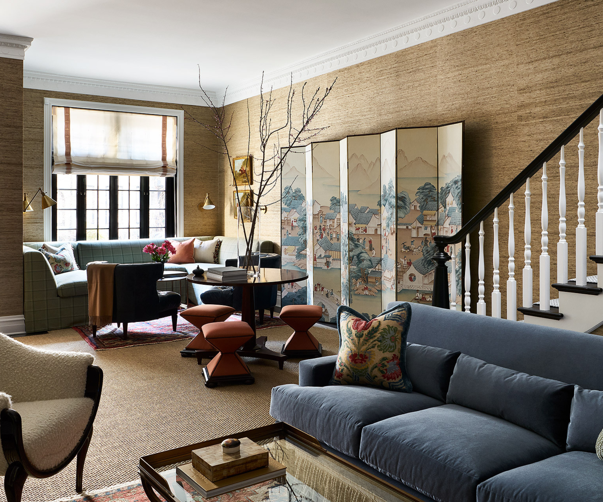 an open concept room with different sitting areas, textured walls, a decorative partition, and an overall warm neutral color scheme