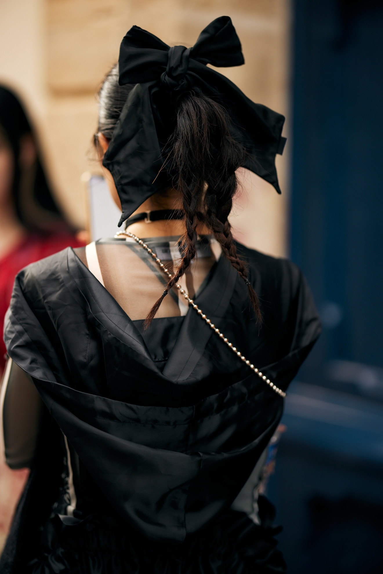 a woman with a black bow in her hair shot from the back wearing a black jacket
