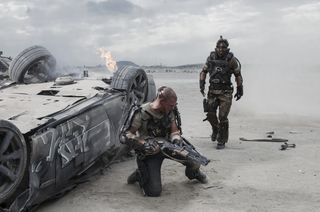 In the future, cars will still flip upside-down. Matt Damon (left) and Sharlto Copley in Columbia Pictures' "Elysium," opening August 9, 2013.