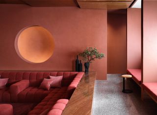 Living room with earthy red walls, sunken seating area with red sofa, and deep walnut woodwork and ceiling