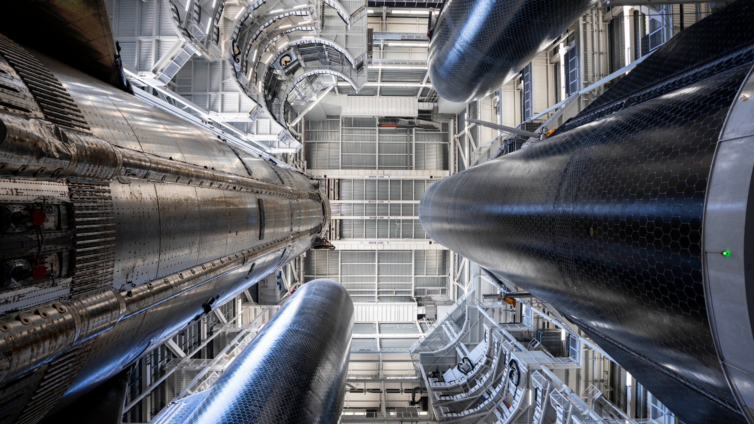 3 a giant rocket stages stand inside a hanger.