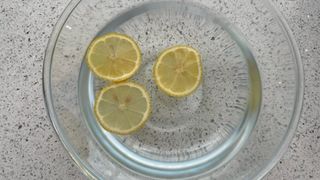 a bowl full of lemon and water in a kitchen countertop