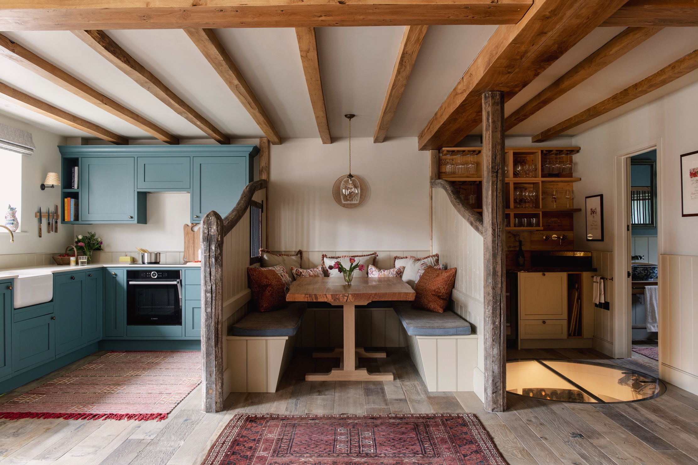 A kitchen and entertaining space. The style is very old english farmhouse, with reclaimed wood, exposed beams and brass fittings
