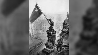 Soviet soldiers fly the Soviet flag over the German Reichstag in Berlin, 1945.