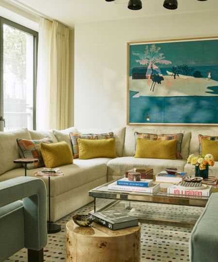 a warm cream open plan apartment living room with a large cream sectional sofa, turquoise wall art and pops of yellow