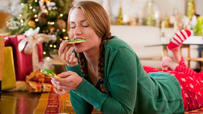 person eating cookies in front of a Christmas tree