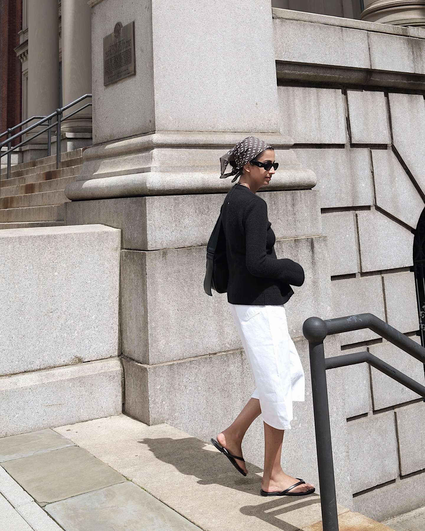 @myskinwears wearing a printed bandana, black top, white Bermuda shorts, and flip-flops.