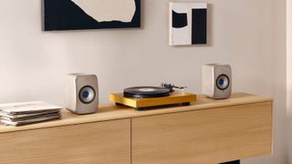 KEF LSX II speaker system on a side table, flanking a turntable.