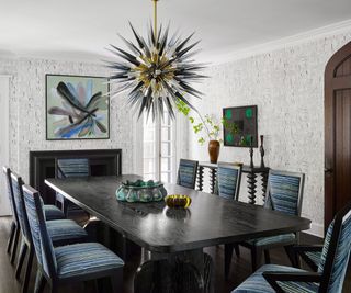 A blue and white dining room with a statement antique chandelier over the table